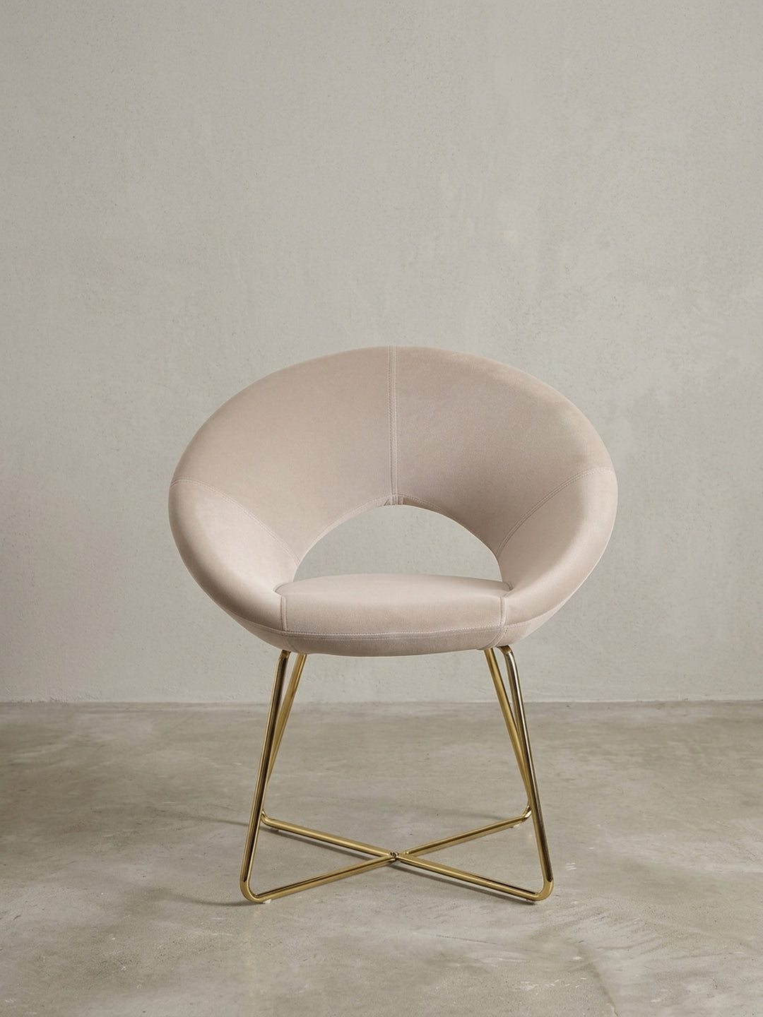 Esszimmerstuhl in Samt Beige aus der Dreiviertelperspektive, zeigt die geschwungene Sitzschale und die elegant gekreuzten goldenen Stuhlbeine._