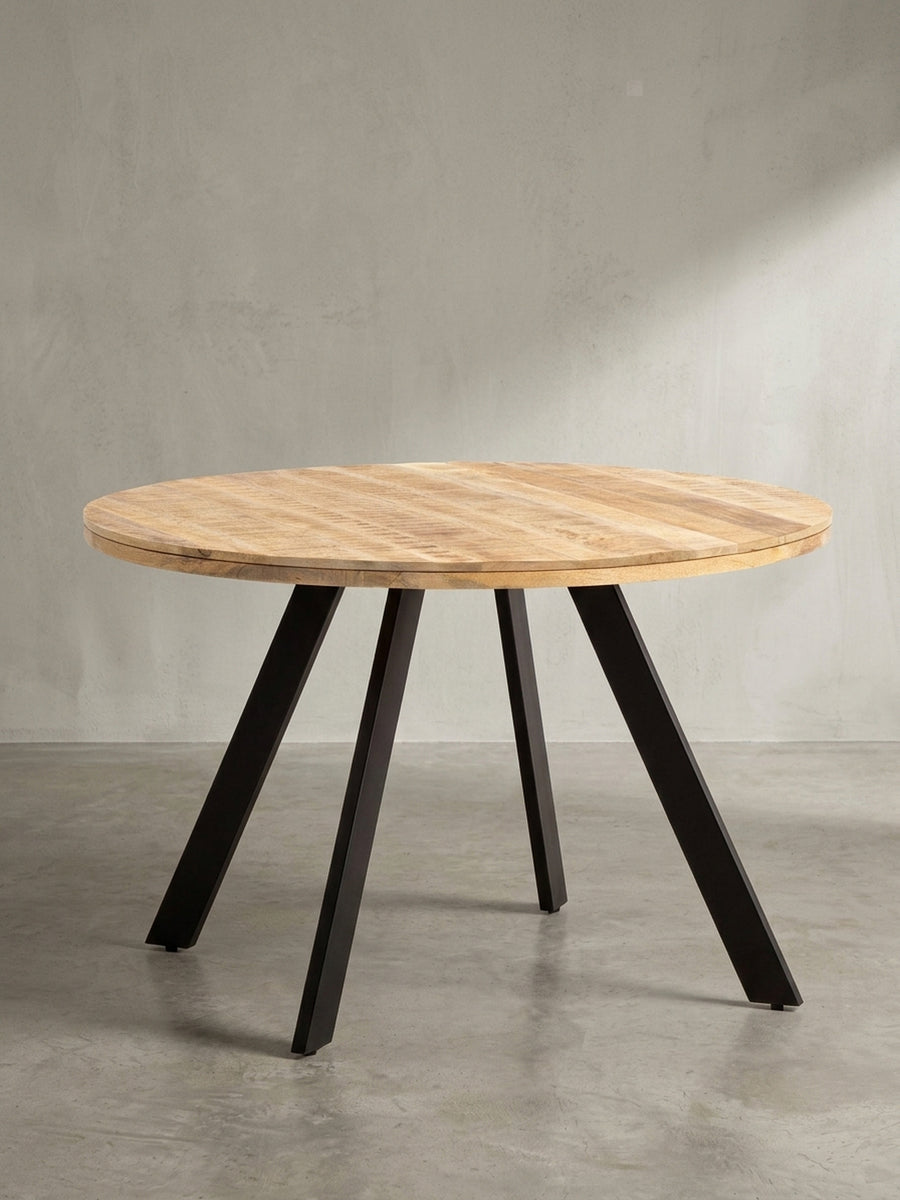 Schräge 3/4-Ansicht des massiven Esstisches, die die stabile Konstruktion der vier konischen, schwarzen Eisenbeine zeigt._