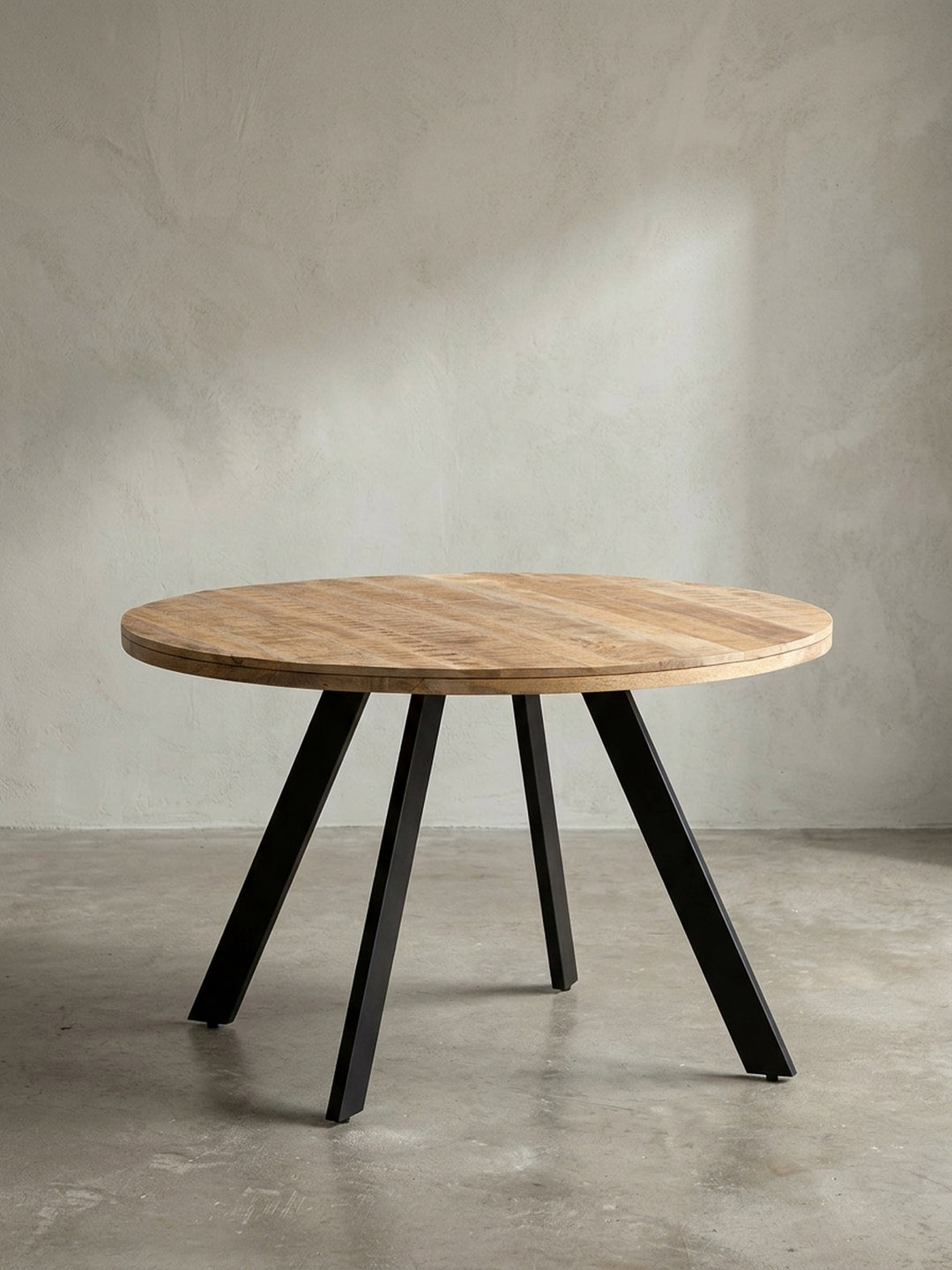 Runder Esszimmertisch 120 cm aus hellem Mangoholz mit rustikaler Oberfläche und schwarzen Metallbeinen, Frontalansicht auf weißem Hintergrund._