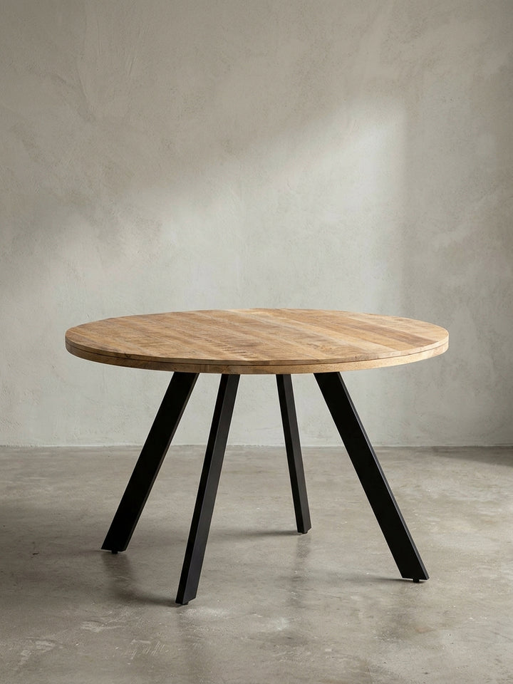 Runder Esszimmertisch 120 cm aus hellem Mangoholz mit rustikaler Oberfläche und schwarzen Metallbeinen, Frontalansicht auf weißem Hintergrund._