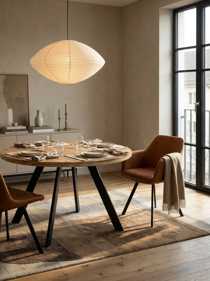 Moderner Esstisch aus Holz kombiniert mit schwarzen Schalenstühlen und einem Sideboard aus Eiche vor einer petrolfarbenen Wand._