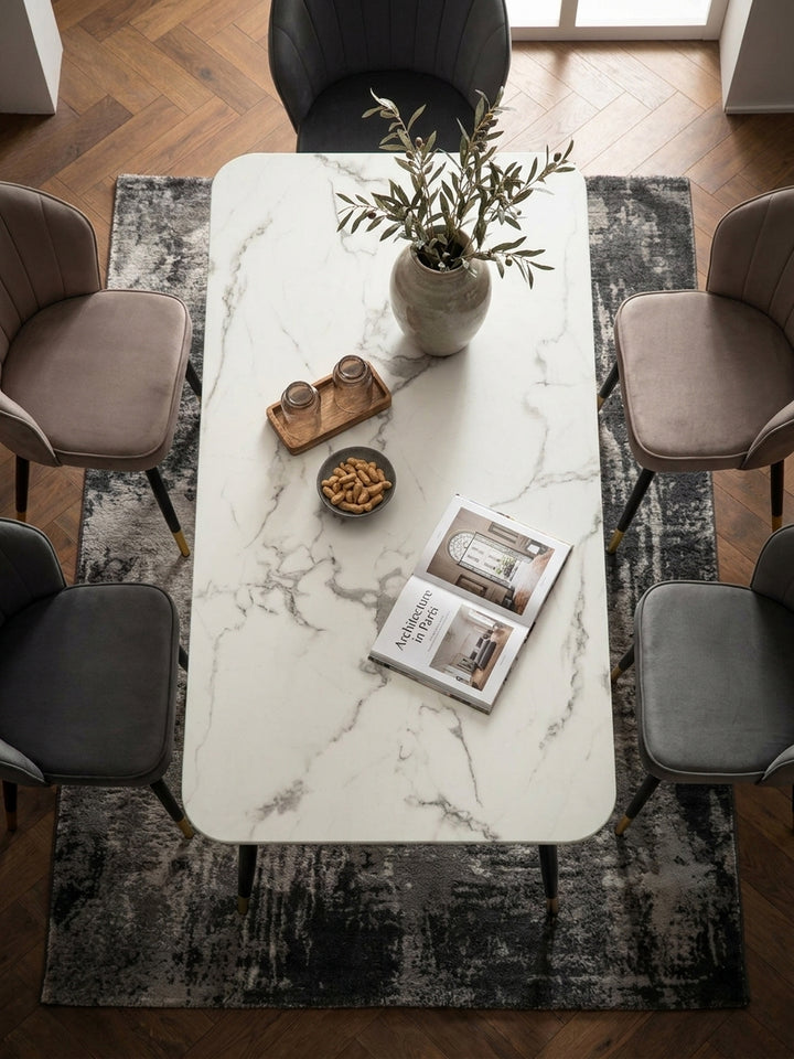 Aufsicht auf einen 140x80 cm großen Küchentisch mit Marmor-Dekor und vier gepolsterten Esszimmerstühlen auf einem edlen Holzboden_