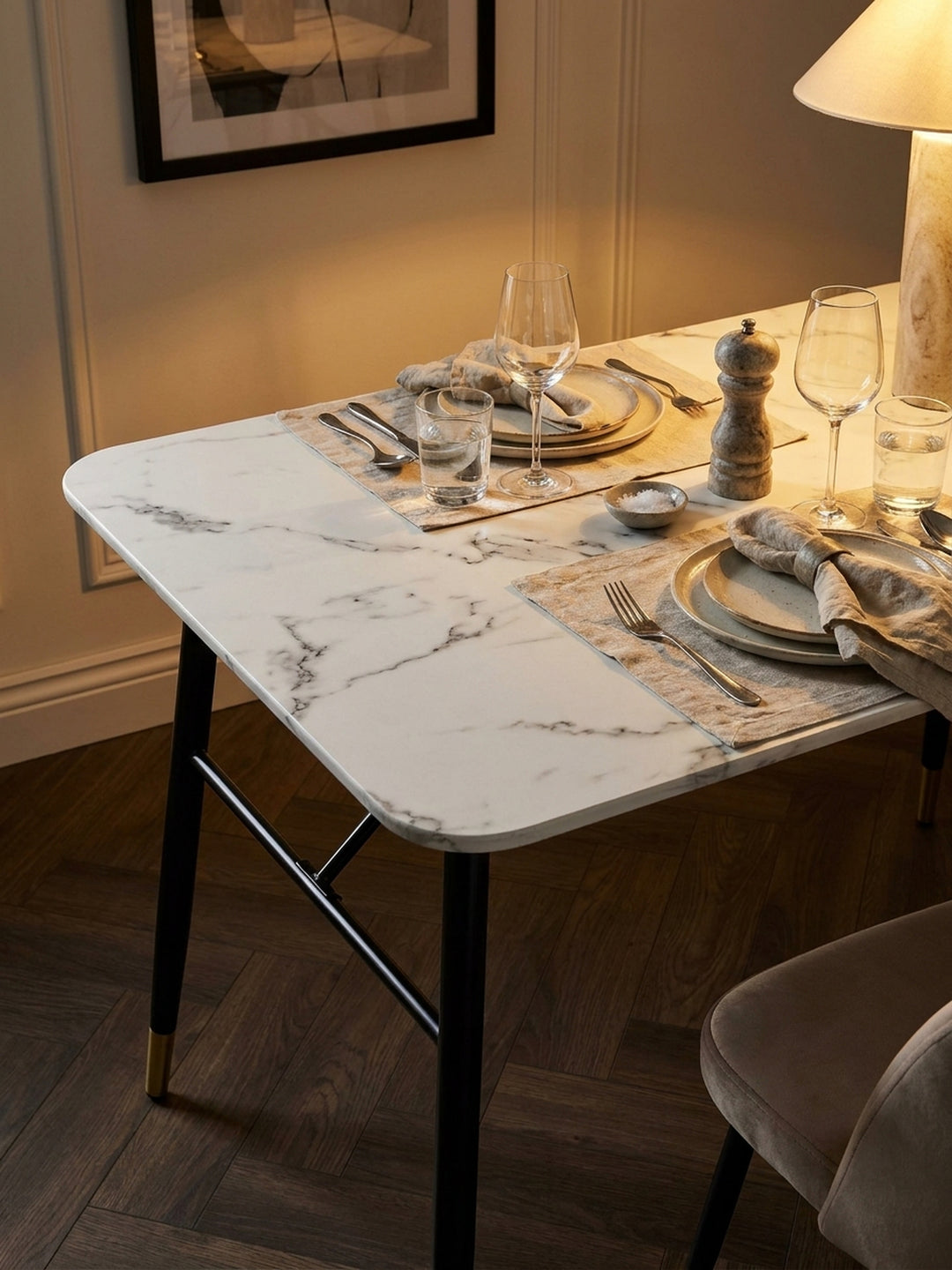 Eleganter Speisetisch mit messingfarbenen Fußkappen, darauf eine gläserne Karaffe und zwei Wassergläser im sonnendurchfluteten Raum_