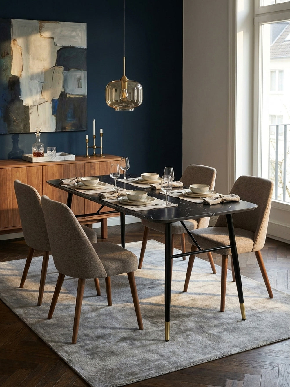 Schwarzer Tisch mit Metallgestell kombiniert mit eleganten Esszimmerstühlen unter einer skulpturalen Messingpendelleuchte im großzügigen offenen Wohn- und Essbereich._