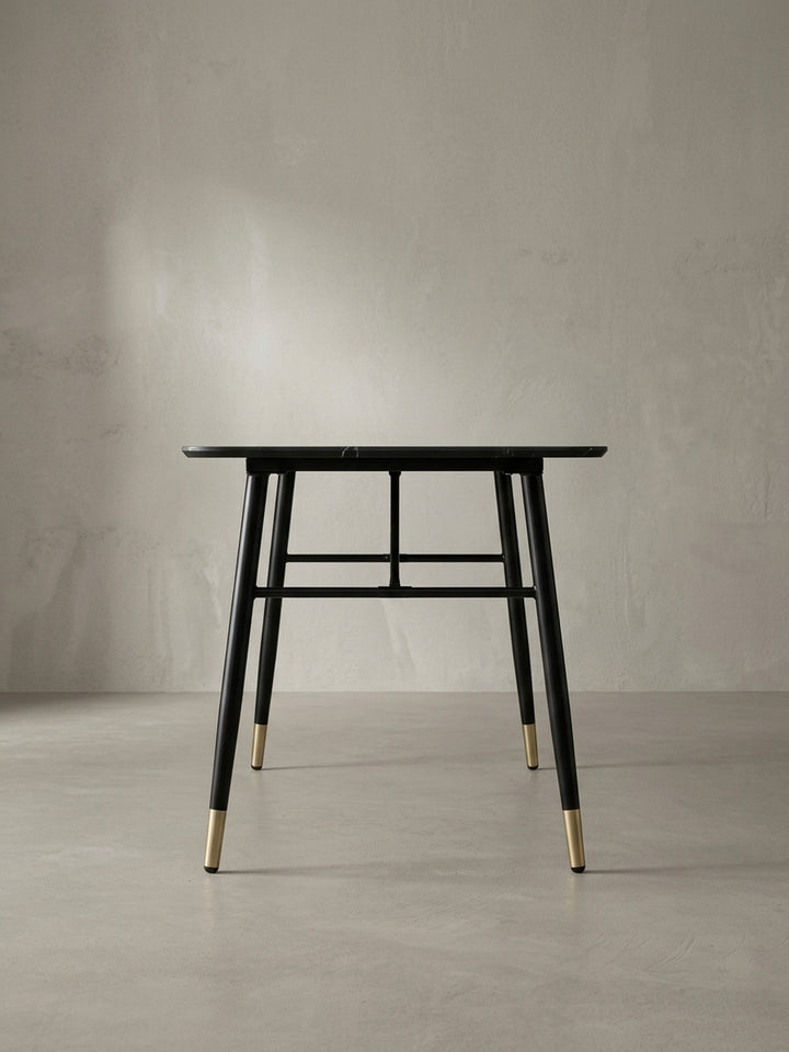 Seitliche Perspektive des eleganten Speisetisches 140x80x76 cm bei der die leicht ausgestellten schwarzen Eisenbeine und das schmale Profil der Tischplatte gut sichtbar sind._