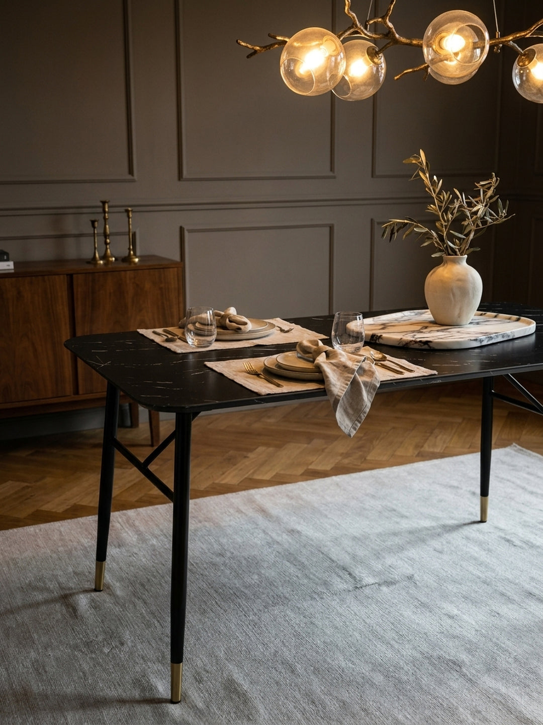 Gemütliches Ambiente am Speisetisch aus dunklem MDF, auf dem eine handgefertigte Keramikvase und ein massives Marmortablett für das elegante Dinner bereitstehen._