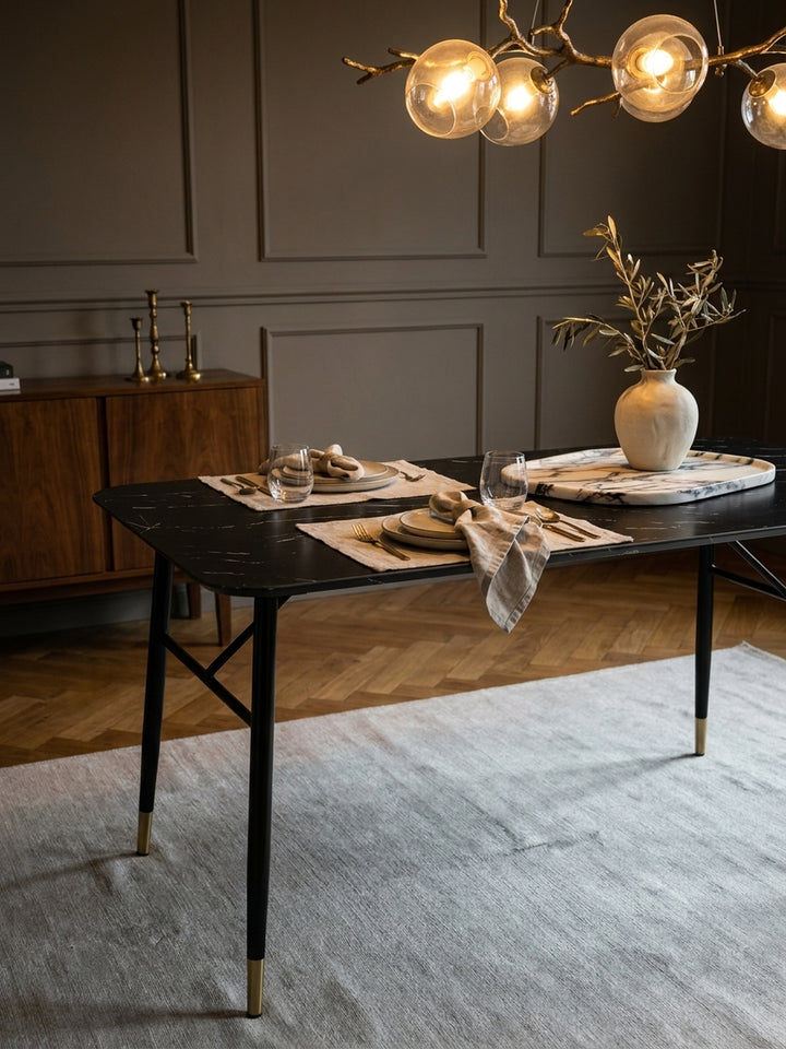 Gemütliches Ambiente am Speisetisch aus dunklem MDF, auf dem eine handgefertigte Keramikvase und ein massives Marmortablett für das elegante Dinner bereitstehen._
