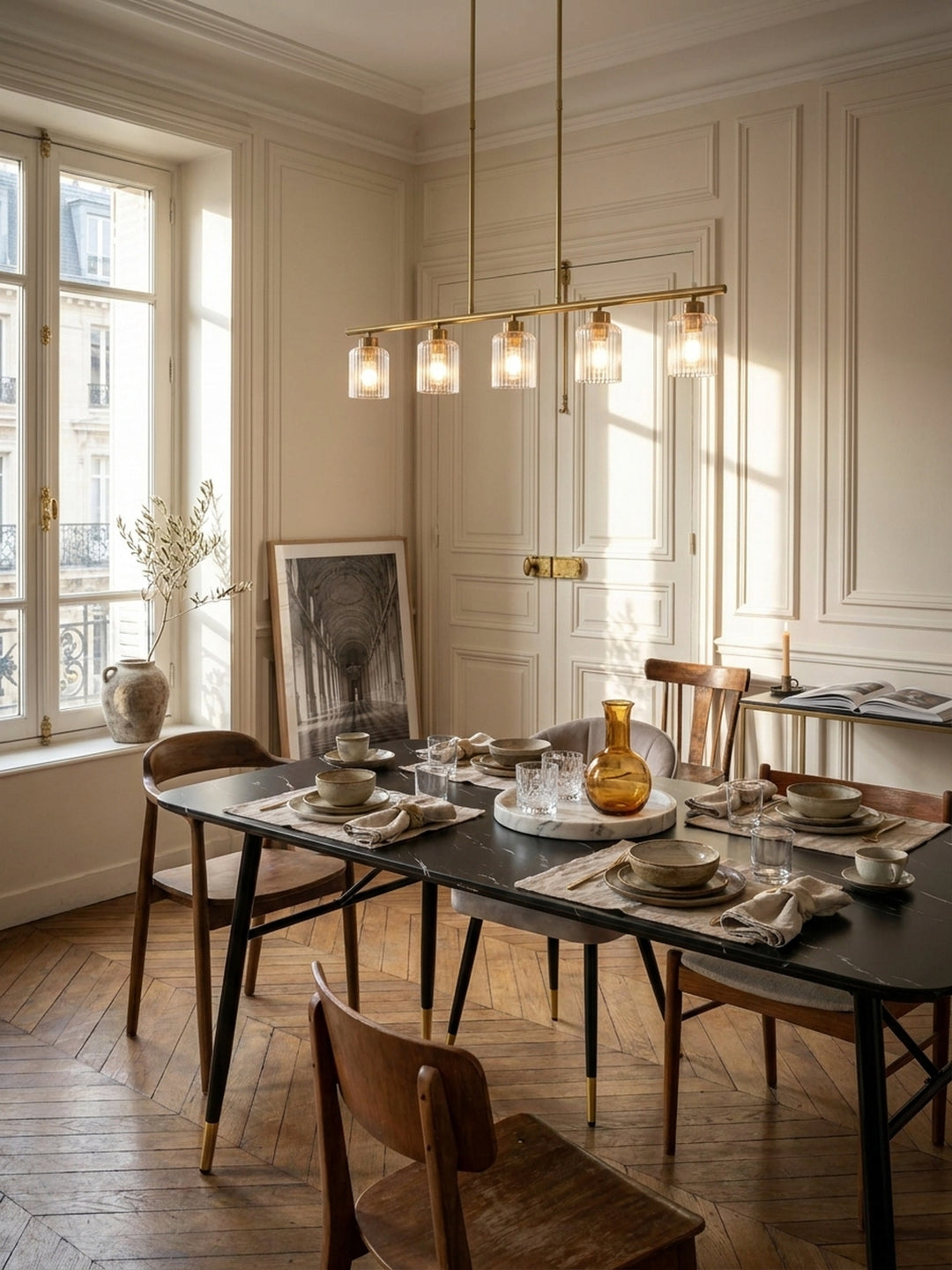 Großer Esstisch in schwarzer Marmor-Optik mit goldenen Fußkappen im eleganten Pariser Esszimmer mit Flügeltüren._