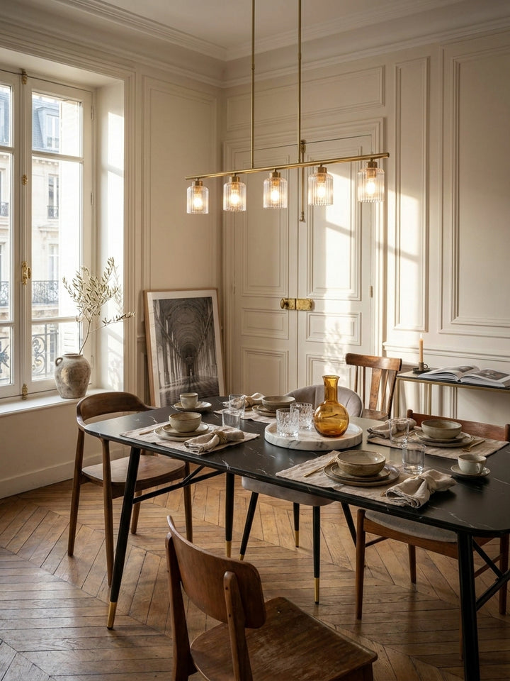 Großer Esstisch in schwarzer Marmor-Optik mit goldenen Fußkappen im eleganten Pariser Esszimmer mit Flügeltüren._