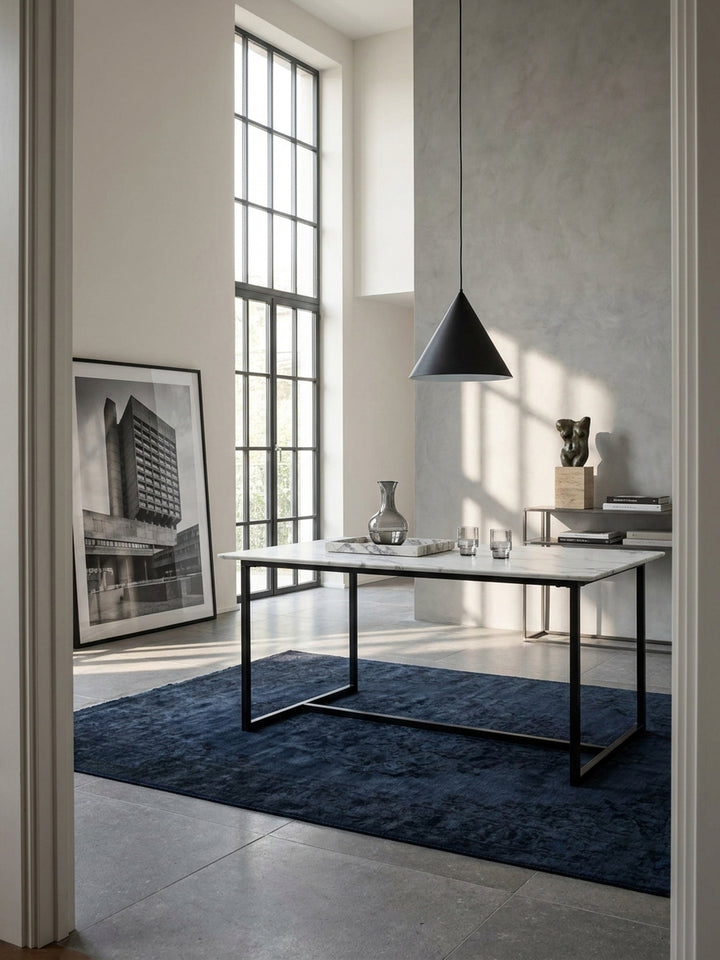 Moderner Esstisch in weißer Marmor-Optik 160x80 cm mit schwarzem Metallgestell freistehend im minimalistischen Esszimmer auf edlem Kalksteinboden._