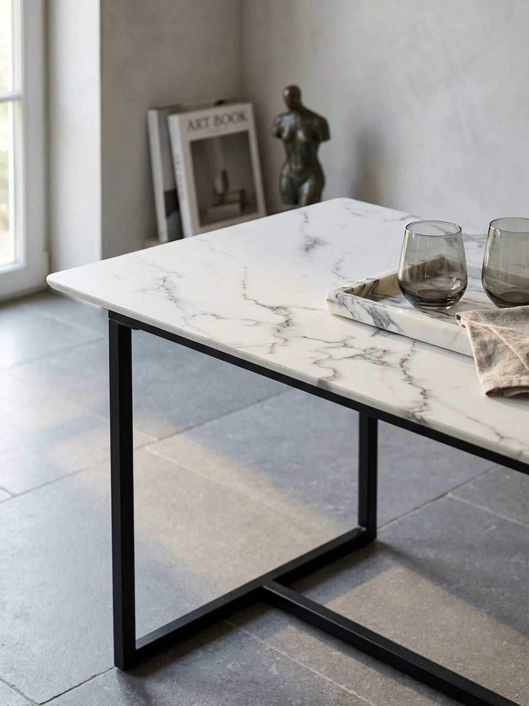 Nahaufnahme der glänzenden weißen Tischplatte aus MDF in Marmor-Optik mit feinen grauen Adern neben einem mattschwarzen Metallprofil._