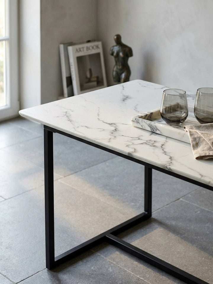 Nahaufnahme der glänzenden weißen Tischplatte aus MDF in Marmor-Optik mit feinen grauen Adern neben einem mattschwarzen Metallprofil._