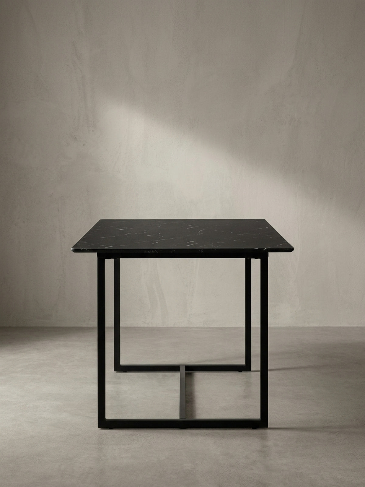 Eleganter Esstisch mit durchgehender Bodenstrebe am schwarzen Metallgestell freigestellt in Schrägansicht von der rechten Seite_