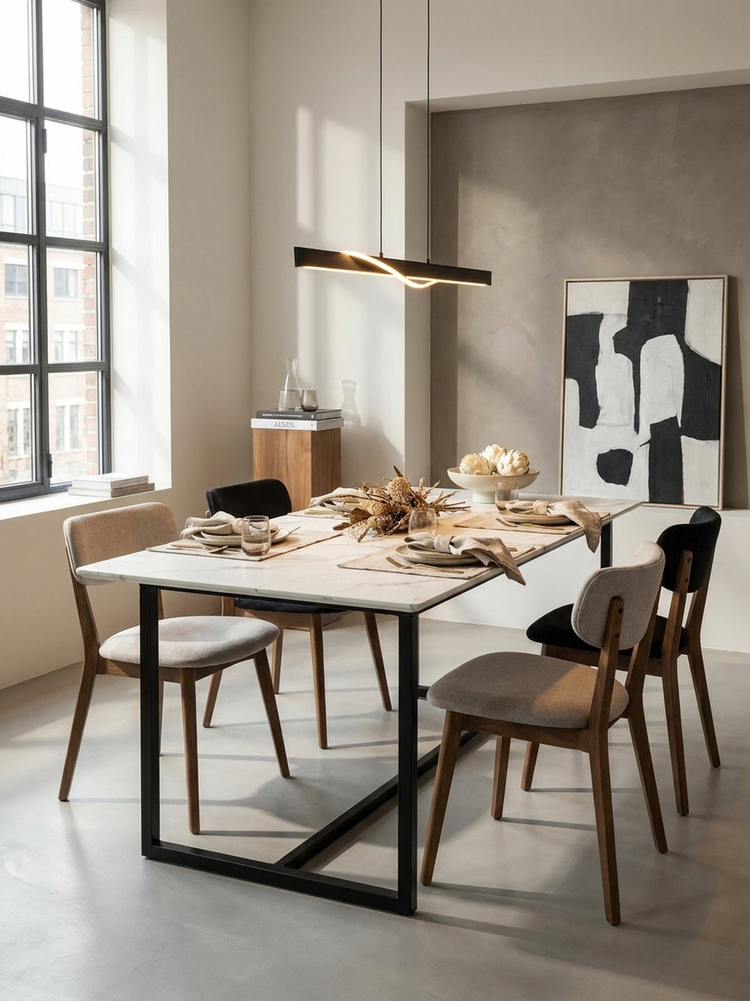 Minimalistischer Esszimmertisch neben weichen Polsterstühlen, elegant inszeniert unter einer schwarzen linearen Pendelleuchte in einem weitläufigen Apartment._