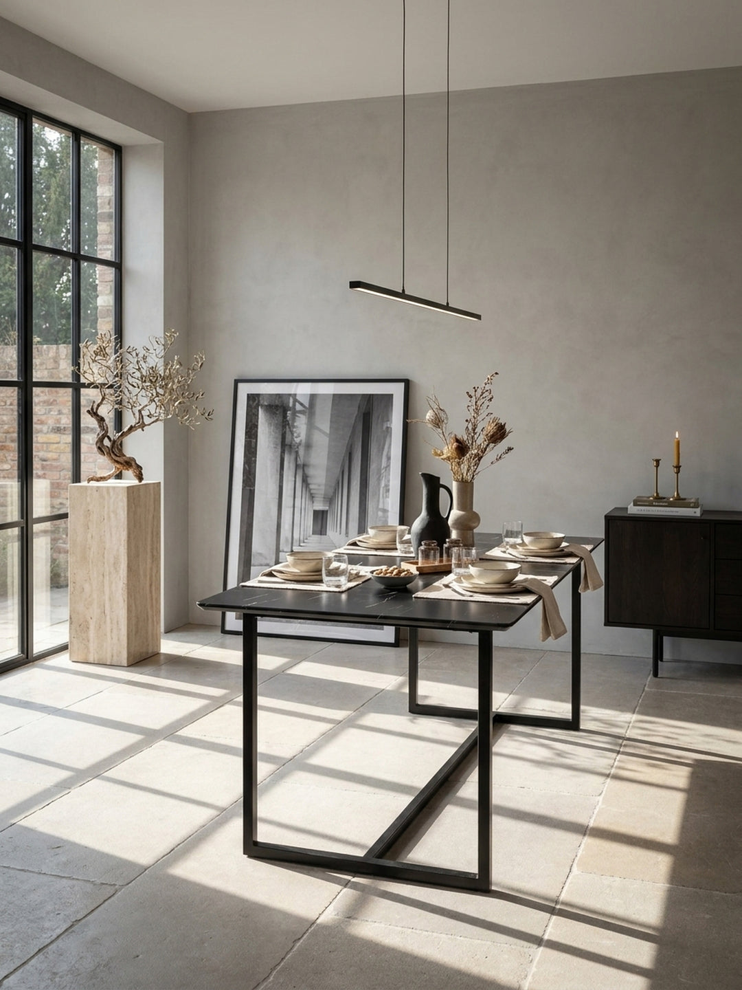 Großer schwarzer Esstisch in glänzender Marmor-Optik 180x90x76 cm im minimalistischen Esszimmer vor hellgrauer Wand auf geschliffenem Kalksteinboden_
