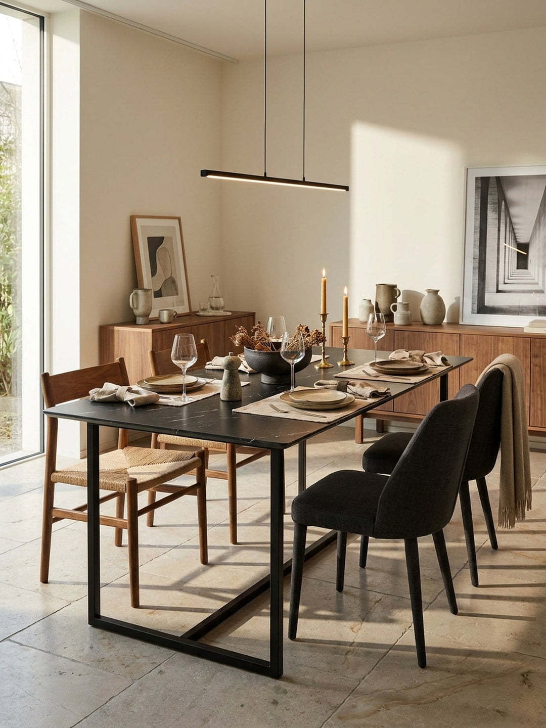 Moderner Küchentisch 200x90 cm in tiefem Schwarz kombiniert mit filigranen Stühlen unter einer sehr eleganten linearen Pendelleuchte_