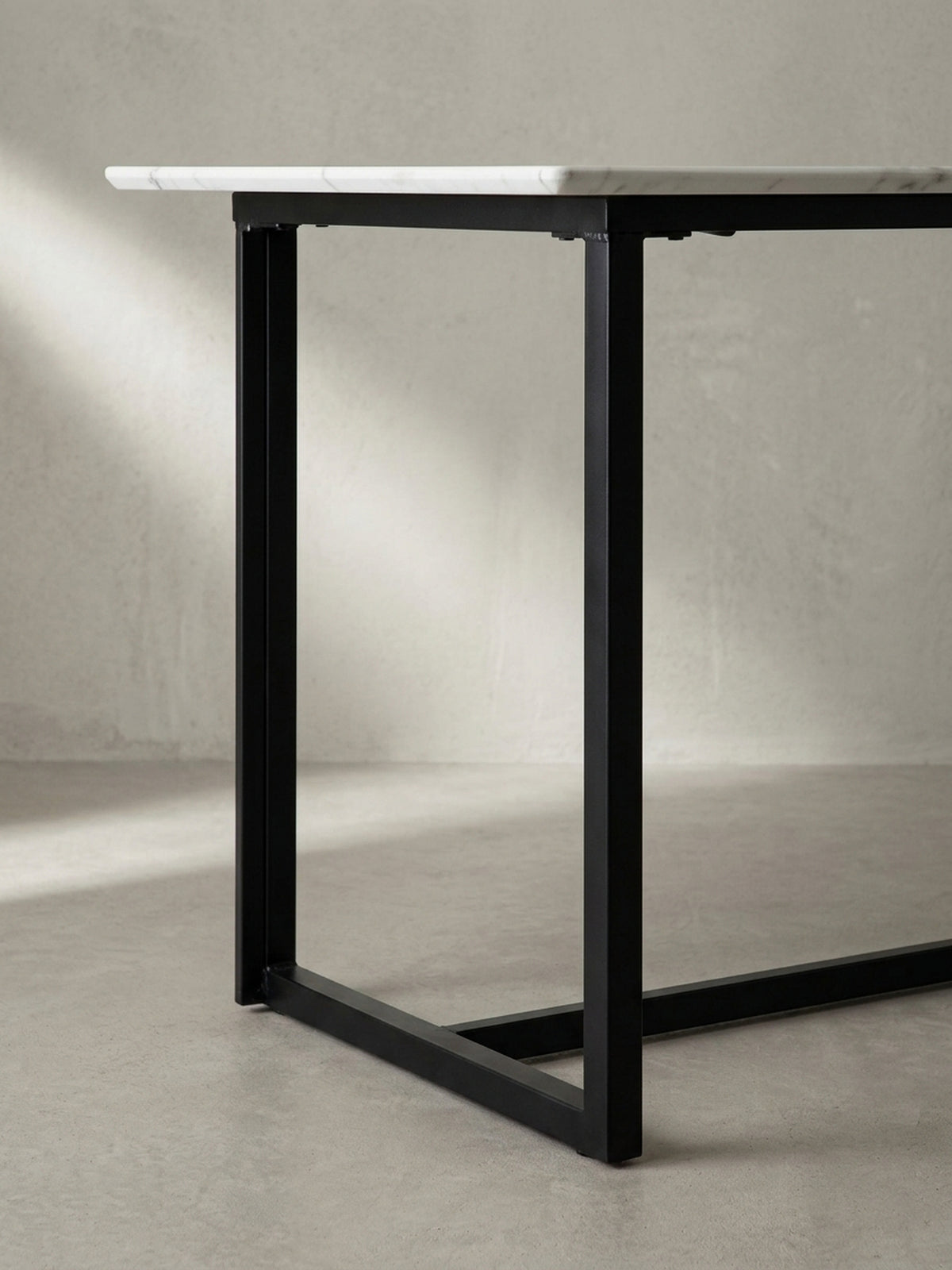 Makroaufnahme der perfekten Verbindungsstellen zwischen der glänzenden Tischplatte im Marmor-Design und dem mattschwarzen Eisenprofil des Tischgestells