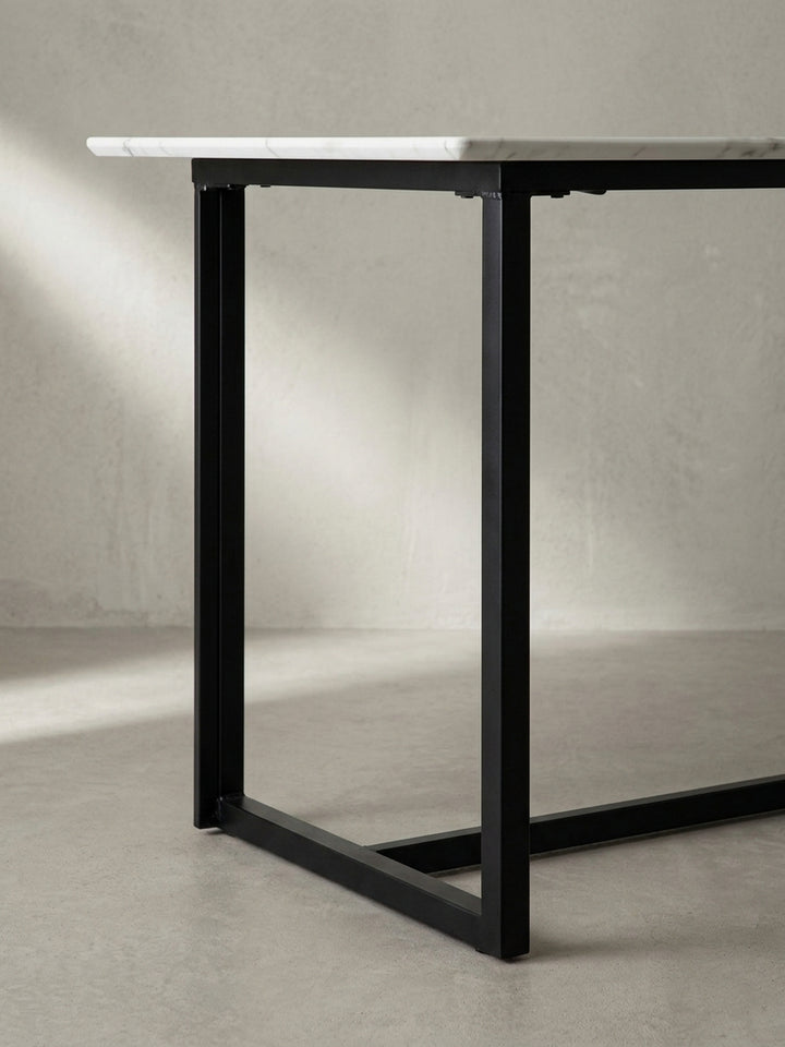 Makroaufnahme der perfekten Verbindungsstellen zwischen der glänzenden Tischplatte im Marmor-Design und dem mattschwarzen Eisenprofil des Tischgestells_