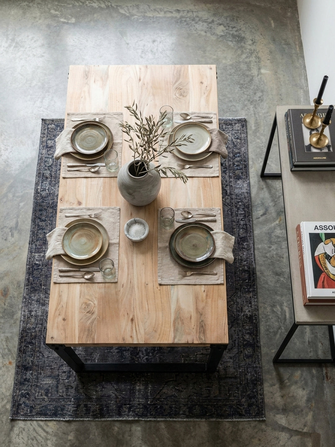 Draufsicht auf einen großzügigen Akazien-Massivholz-Esstisch mit schwarzem Kufengestell im modernen Esszimmer arrangiert auf einem verblassten Vintage-Teppich._