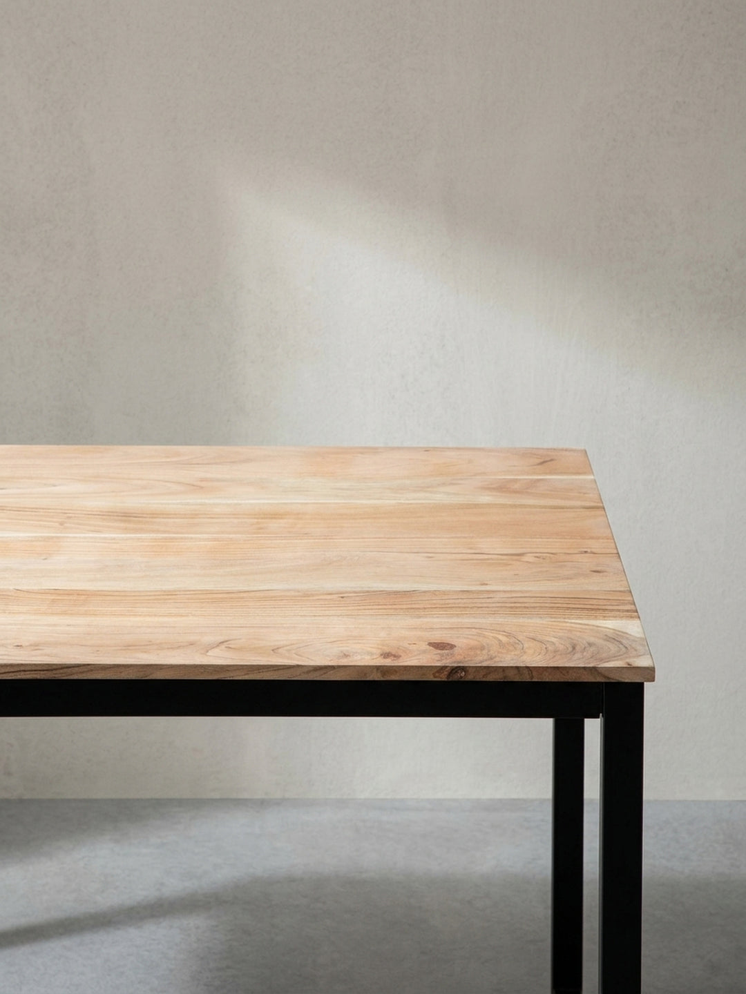 Versetzte Perspektive auf den Loft-Tisch aus Naturholz betont die harmonische Kombination aus organischem Material und kühlem Industriestahl_