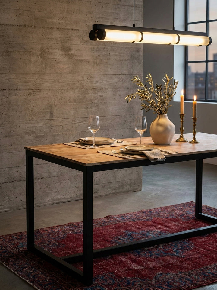 Stilvoll gedeckter Esstisch aus Massivholz mit einer rustikalen Keramikvase und schweren Messingkerzenständern auf einem burgunderroten Vintage-Teppich_