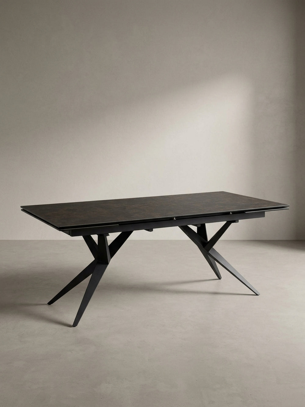 Seitenprofil des großen Keramiktisches, das die schlanke Silhouette der Platte im Kontrast zum massiven, kunstvollen Untergestell hervorhebt._