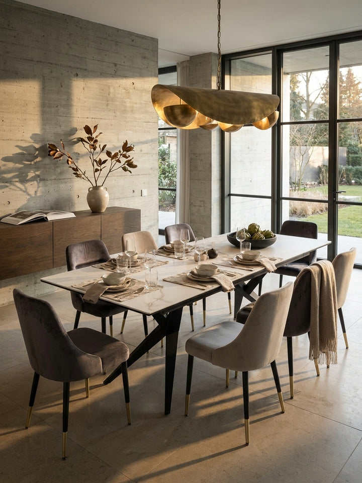 Der extravagante Esstisch mit skulpturalen Metallbeinen kombiniert mit dunkelgrauen Samtstühlen für ein luxuriöses Ambiente._