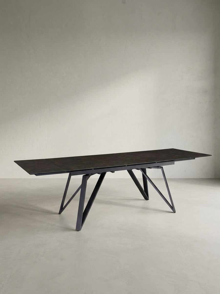 Seitenprofil des schwarzen Keramiktisches, das die schlanke Linienführung der Tischplatte im Kontrast zum markanten Design der Metallbeine hervorhebt._