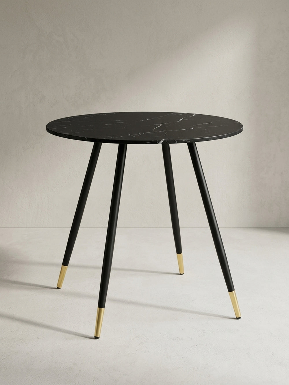 Moderner Esstisch in Marmor-Optik aus der Dreiviertelperspektive, die schlanken, konisch zulaufenden Metallbeine betonend._