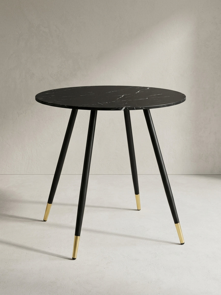 Moderner Esstisch in Marmor-Optik aus der Dreiviertelperspektive, die schlanken, konisch zulaufenden Metallbeine betonend._