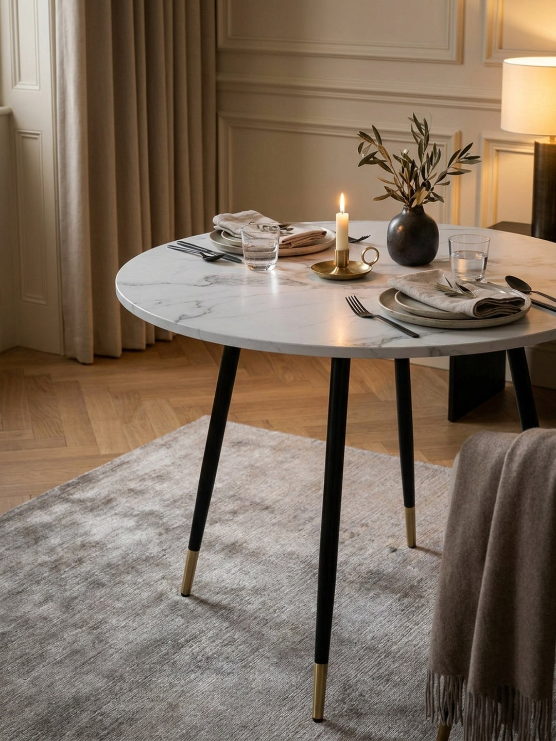 Gemütliches Frühstücks-Setting auf einem modernen runden Esstisch neben einer Espressotasse und einer Keramikvase mit getrockneten Eukalyptuszweigen_