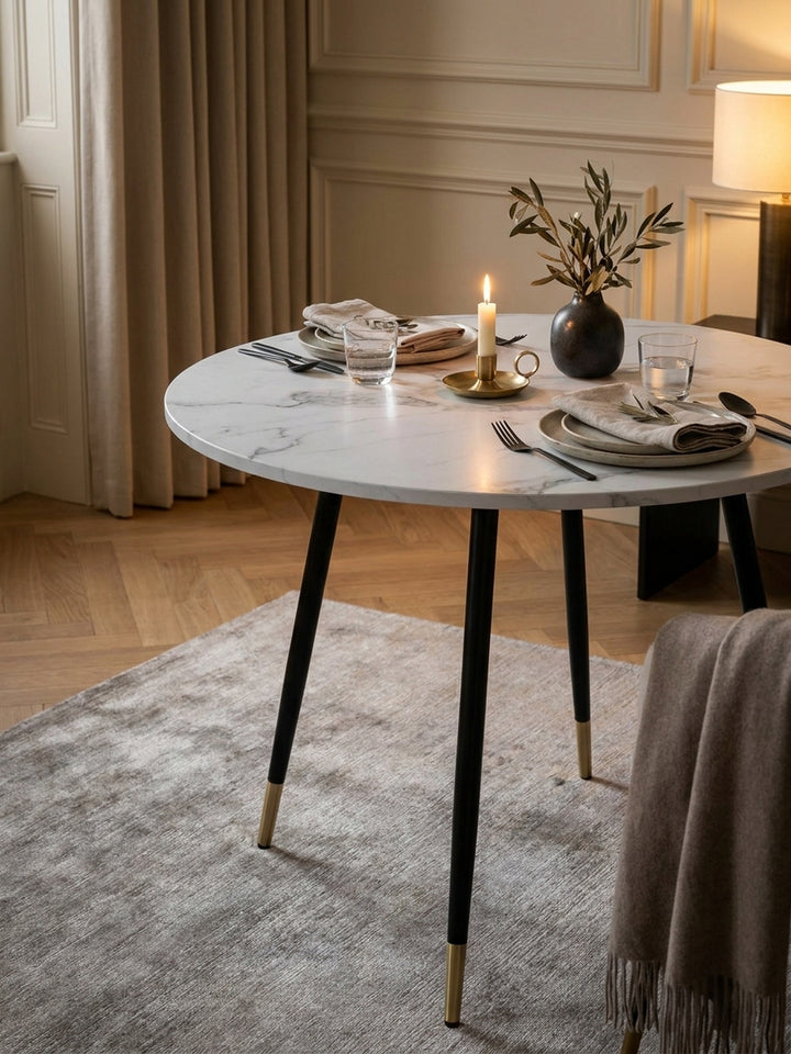 Gemütliches Frühstücks-Setting auf einem modernen runden Esstisch neben einer Espressotasse und einer Keramikvase mit getrockneten Eukalyptuszweigen_