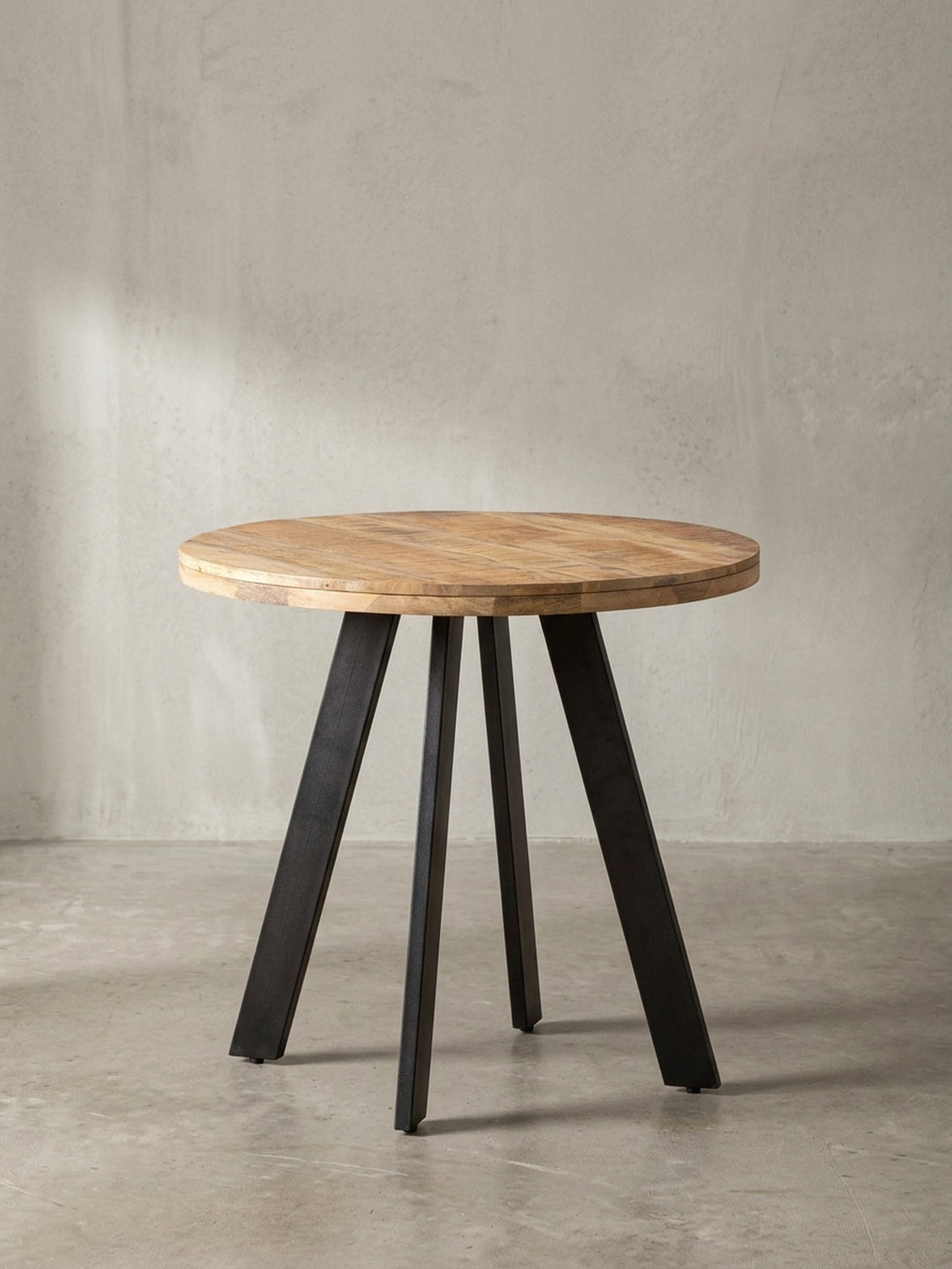 Der Esszimmertisch aus Mango Massivholz in der 3/4-Ansicht, die den Kontrast zwischen Holz und Metallbeinen zeigt._