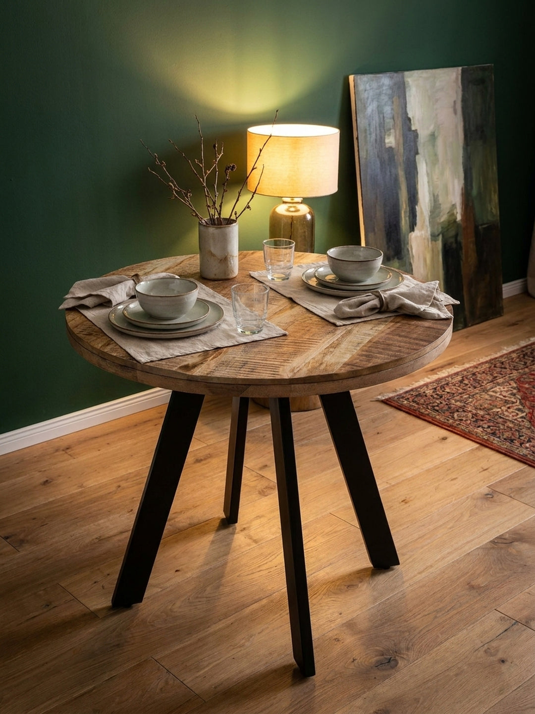 Detailansicht des Küchentisches aus Holz, auf dem zwei schwarze Kaffeetassen und eine Vase mit Trockenblumen stehen._