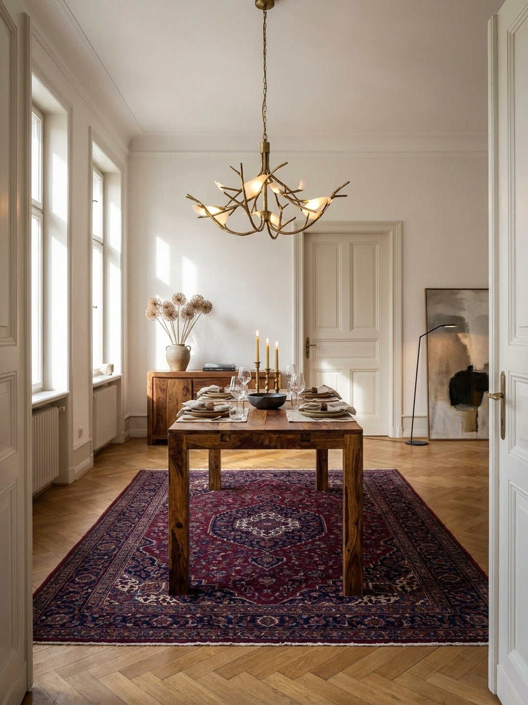 Esszimmertisch aus massivem Sheeshamholz als Mittelpunkt eines eleganten Esszimmers mit Fischgrätparkett und hohen Fenstern, für 6-8 Personen._