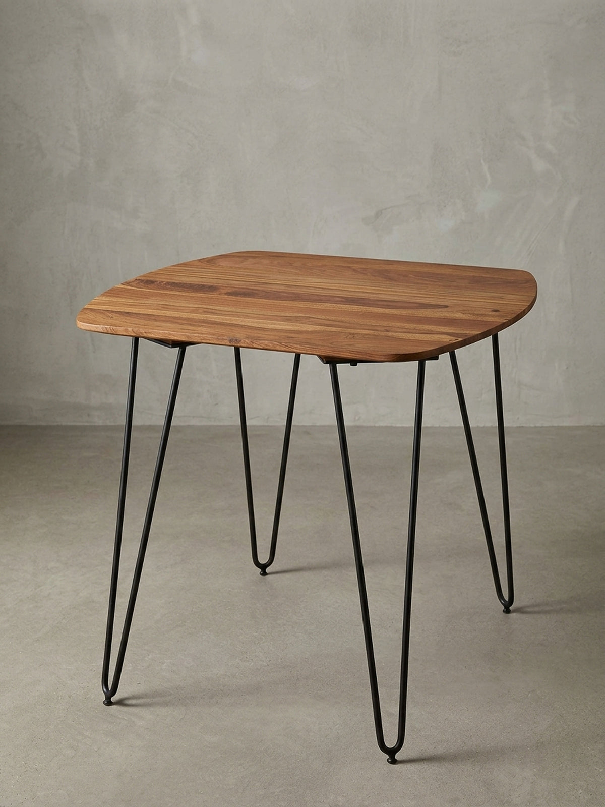 Moderner quadratischer Esstisch mit mattschwarzen Metallbeinen vor weißem Hintergrund. Die 80x80cm große massive Holztischplatte besticht durch ihre abgerundeten, weichen Ecken.