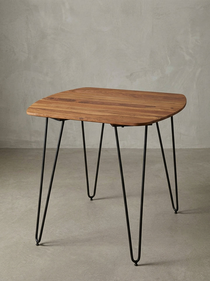 Moderner quadratischer Esstisch mit mattschwarzen Metallbeinen vor weißem Hintergrund. Die 80x80cm große massive Holztischplatte besticht durch ihre abgerundeten, weichen Ecken._