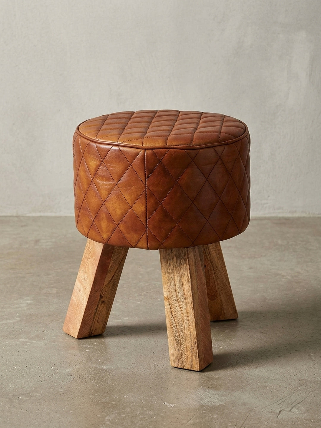 Gesamtüberblick des Design-Hockers, der den Materialmix aus warmem Echtleder und hellem Massivholz zusammenfasst, ideal als kleiner Beistellhocker._