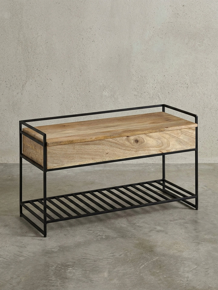 Freigestellte Sitzbank mit Stauraum in 90x52x38 cm, die die Kombination aus massivem Mangoholz und schwarzem Metallgestell zeigt._