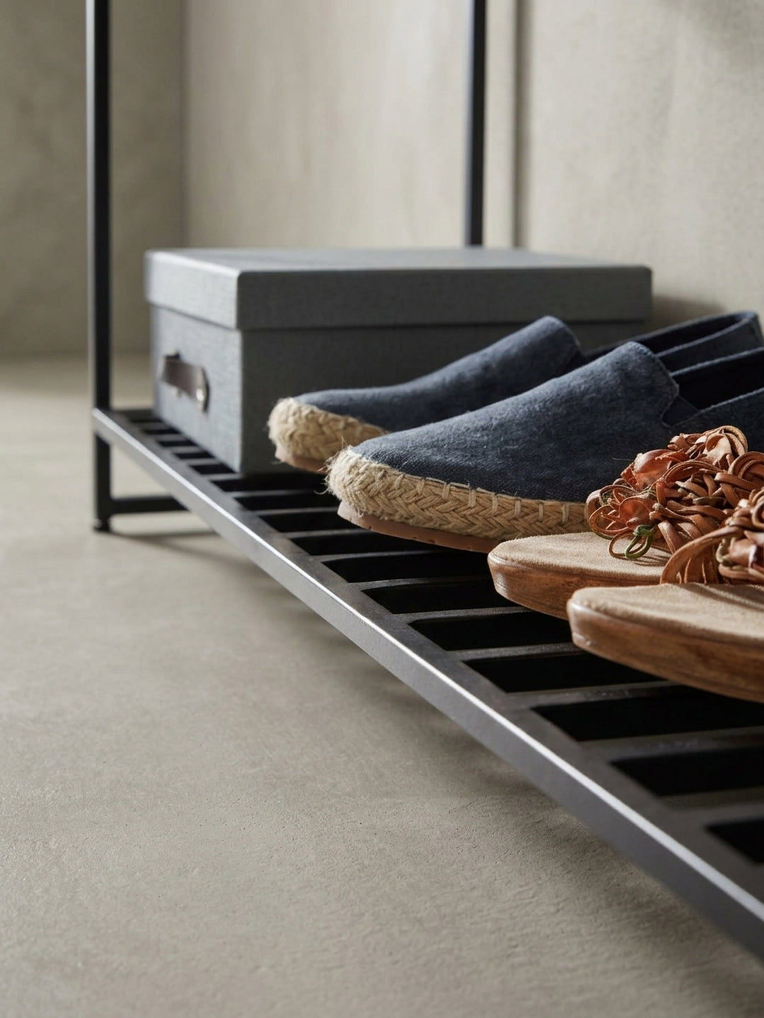 Detailaufnahme des schwarz pulverbeschichteten Schuhregals der Bank, das robusten Halt für mehrere Paar Schuhe bietet._