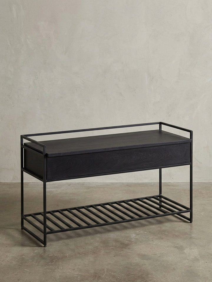 Moderne Sitzbank in Schwarz mit integriertem Schuhregal und Staufach, Frontansicht auf weißem Hintergrund, aus massivem Mangoholz und pulverbeschichtetem Eisen._