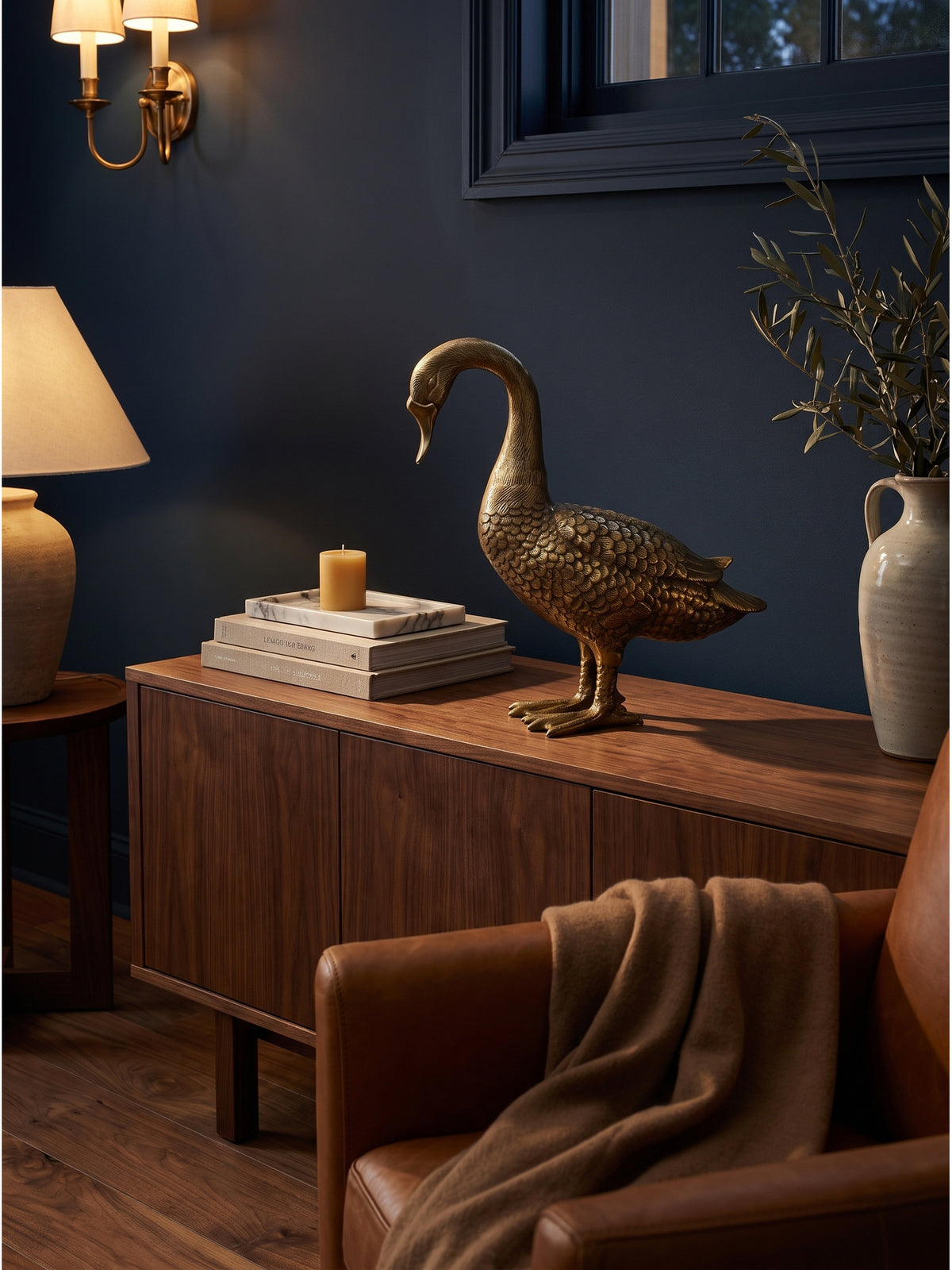 Stimmungsvolles Arrangement mit der 42 cm hohen Aluminiumfigur Gans in Gold neben einer organischen Keramikvase und einem Calacatta-Marmor-Tablett auf einer massiven Holzkonsole.