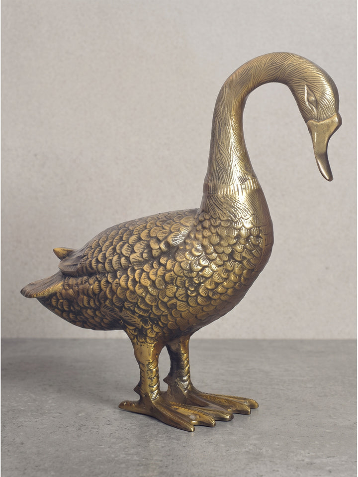 Profilansicht der stehenden Gänsefigur aus goldfarbenem Metall, das robuste und schwere Design mit den detailliert ausgearbeiteten Füßen sorgt für einen sicheren Stand auf Regalen oder Sideboards._