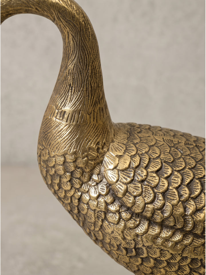 Elegante Tierfigur Gans als modernes Wohnaccessoire aus massivem Aluguss mit goldenem Finish, die feinen, von Hand anmutenden Gravuren des Gefieders fangen das Umgebungslicht stimmungsvoll ein._