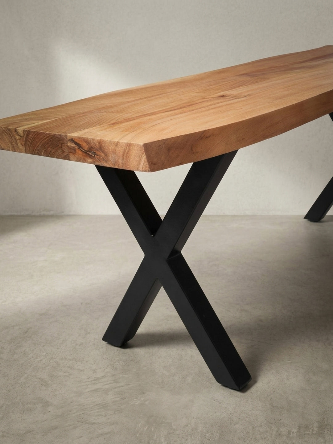Detailaufnahme des präzisen Übergangs vom mattschwarzen X-Bein zur warmen Akazienholz-Sitzfläche, ein Merkmal des modernen Industrial Designs._