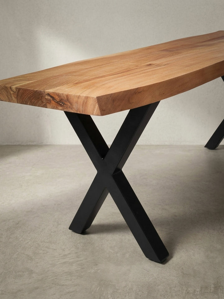 Detailaufnahme des präzisen Übergangs vom mattschwarzen X-Bein zur warmen Akazienholz-Sitzfläche, ein Merkmal des modernen Industrial Designs._