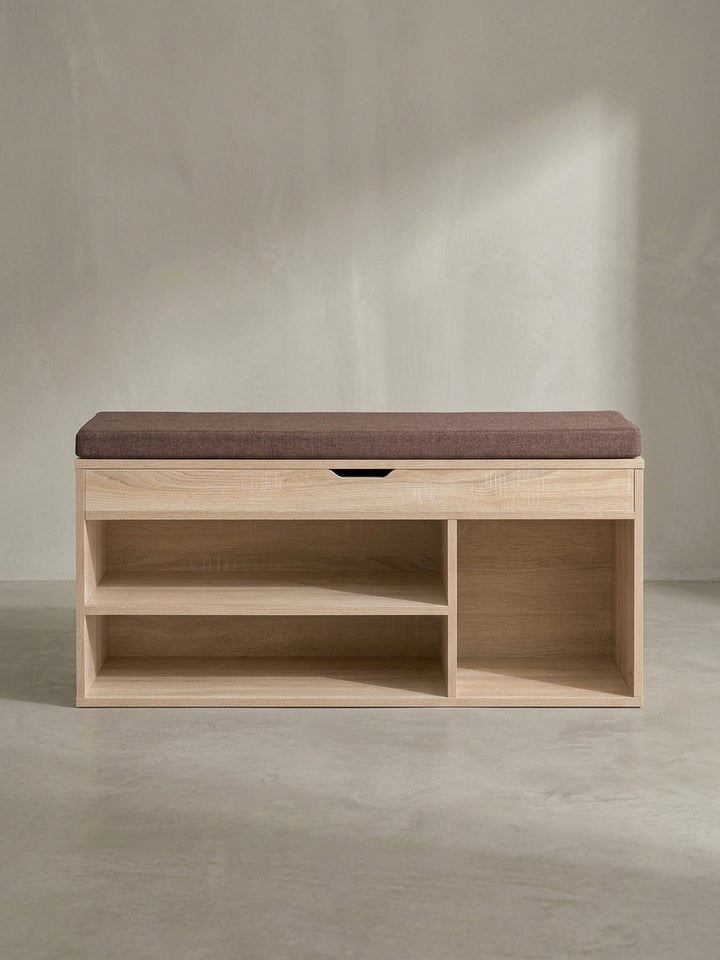 Leicht schräge Perspektive der funktionalen Garderobenbank mit weichem Kissen und eleganter Griffmulde an der Frontklappe_