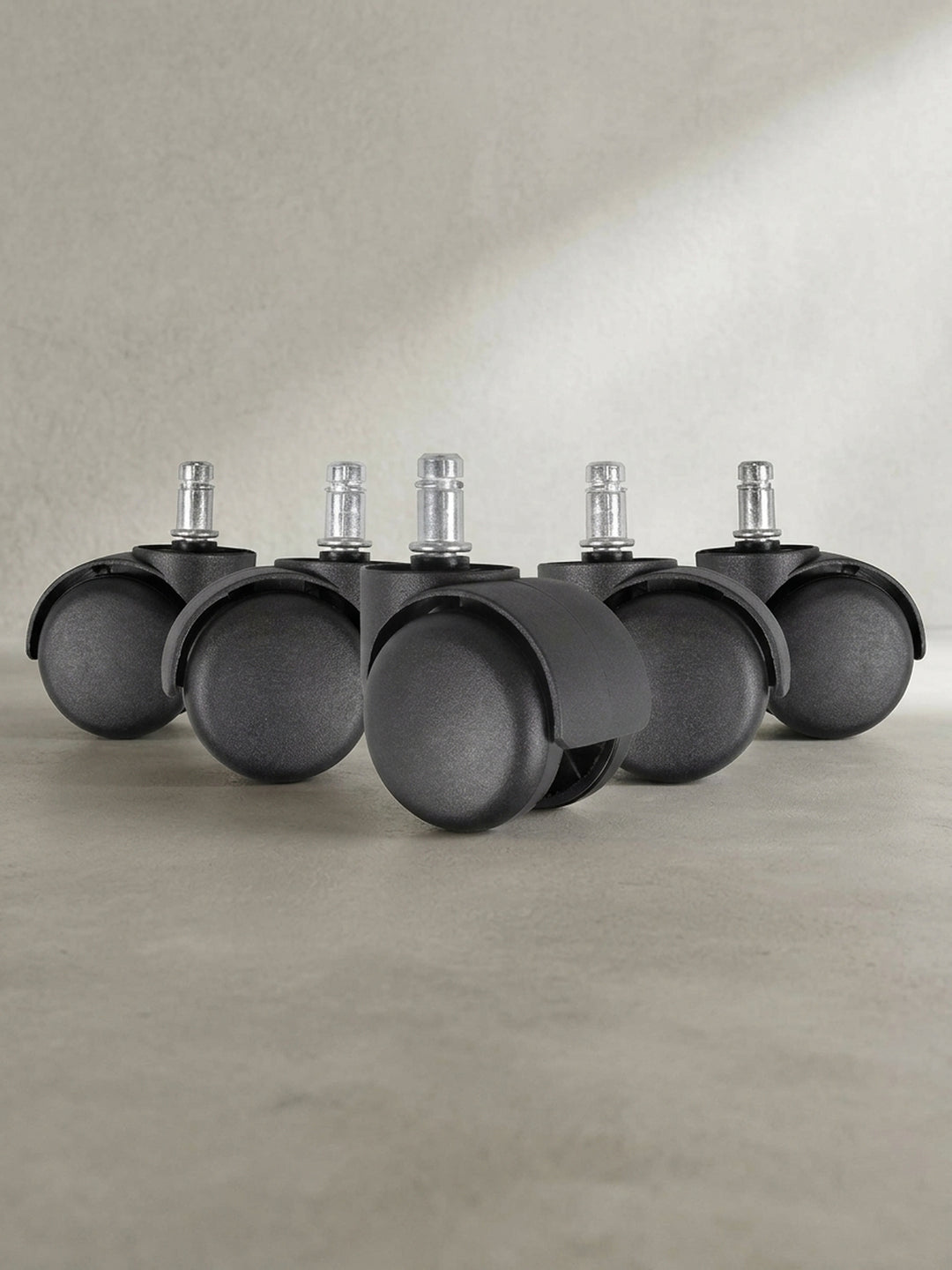 Frontale Ansicht des 5er Sets Weichbodenrollen in Schwarz, ideal für Teppichböden im heimischen Arbeitszimmer._