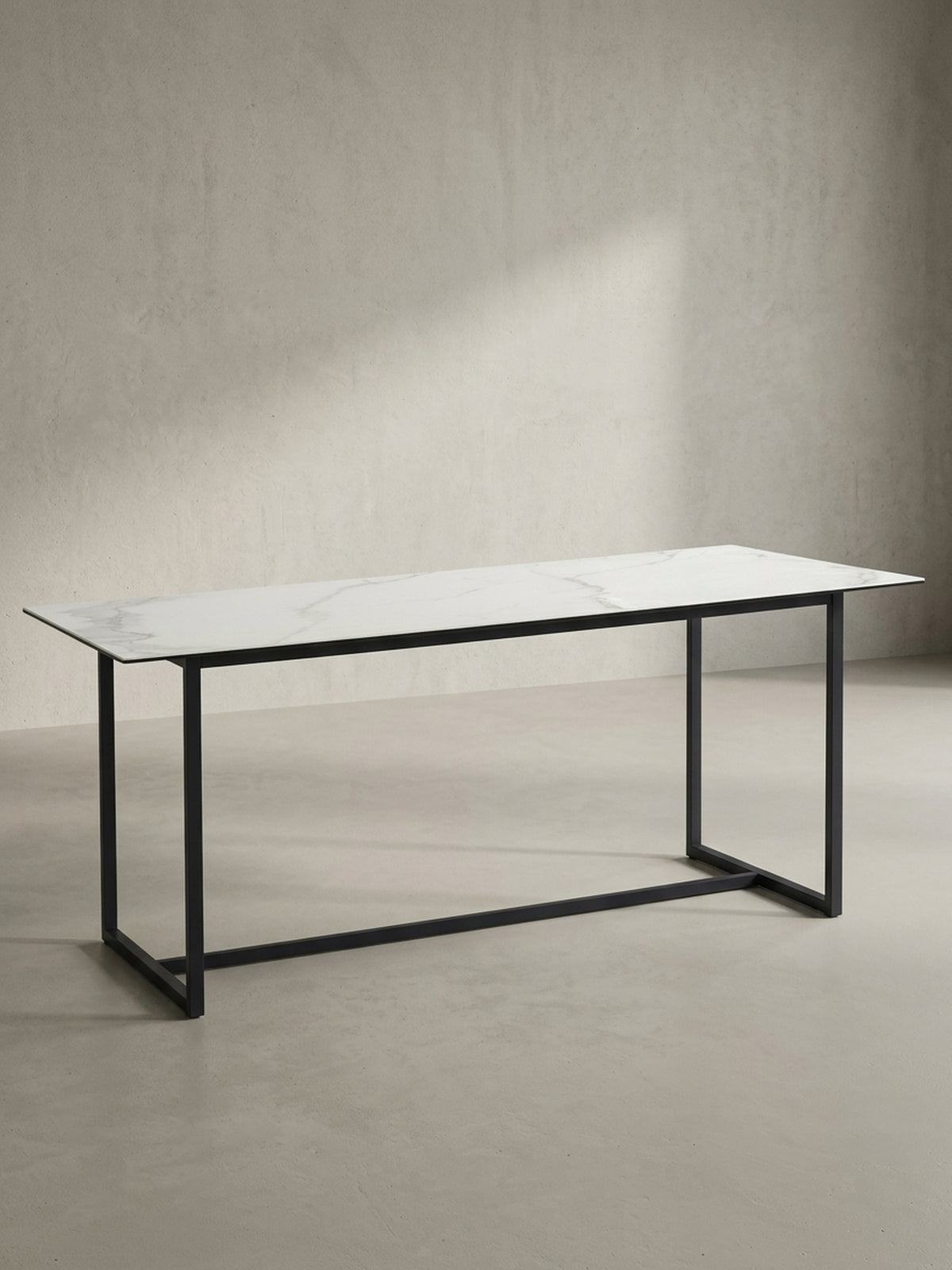 Freigestellter rechteckiger Esstisch 180x90x76 cm mit robuster Keramikplatte in Marmoroptik und mattschwarzen Metallbeinen von vorne links_