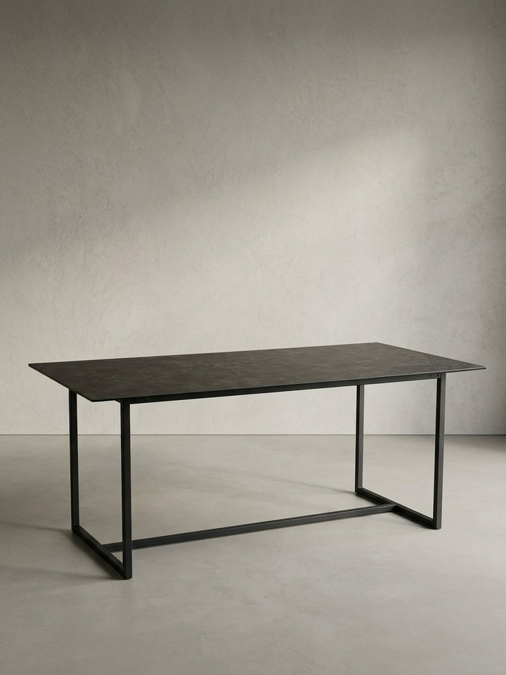 Freigestellter Esstisch 180x90 cm schwarz mit Keramik-Glasplatte und U-förmigem Metallgestell in Schrägansicht_